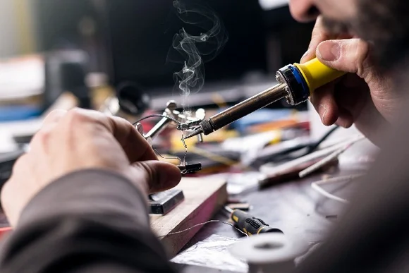 Person lötet mit Lötkolben